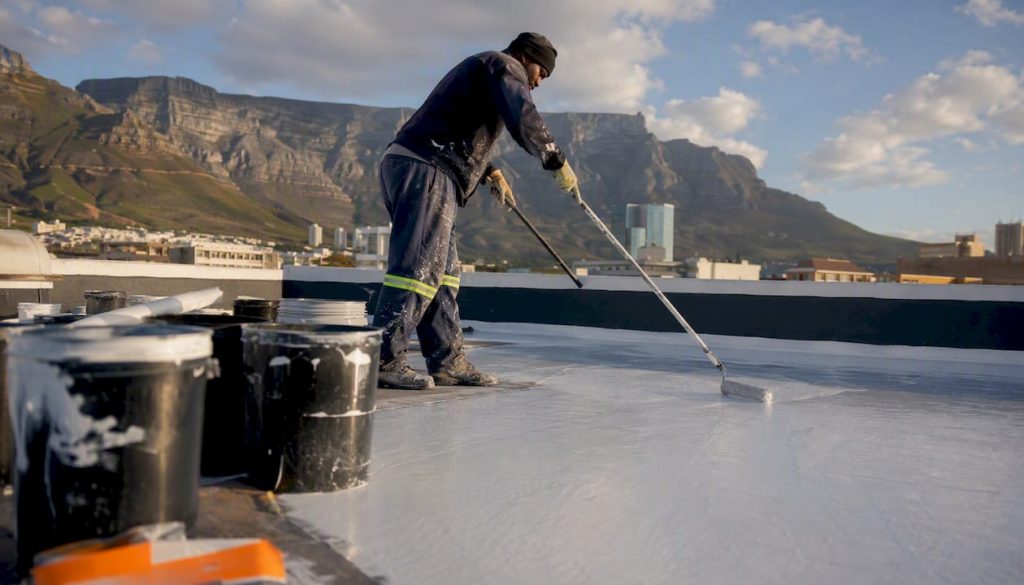 Roofer applying white roof coating with roller