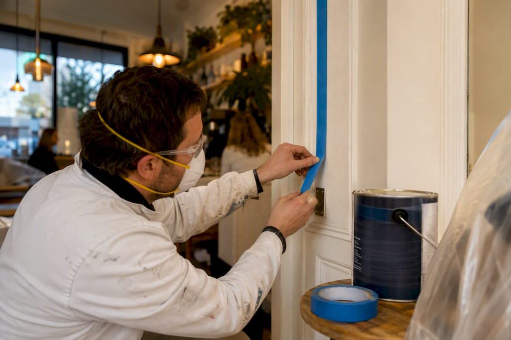 Painter taping edges in occupied building interior