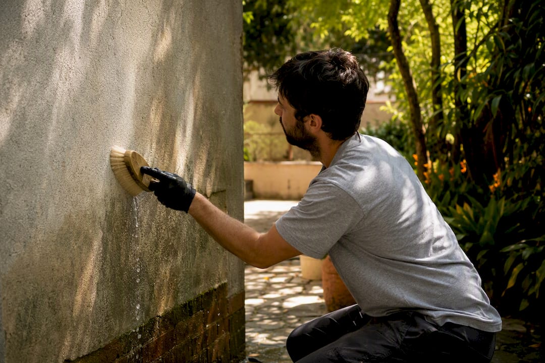 Hand cleaning painted wall with soft brush