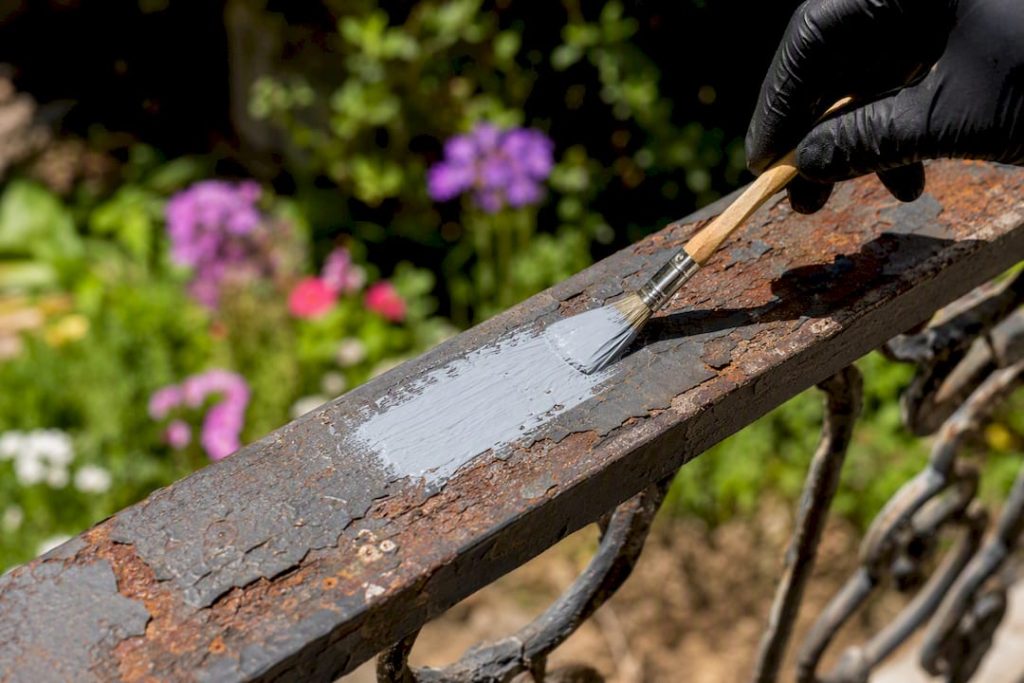 Hand pressing screwdriver on rusted railing