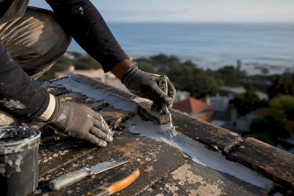 Painter sealing crack on coastal roof